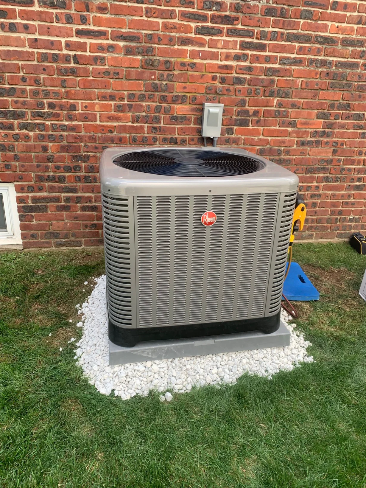 Rheem outdoor AC unit newly installed against a brick wall