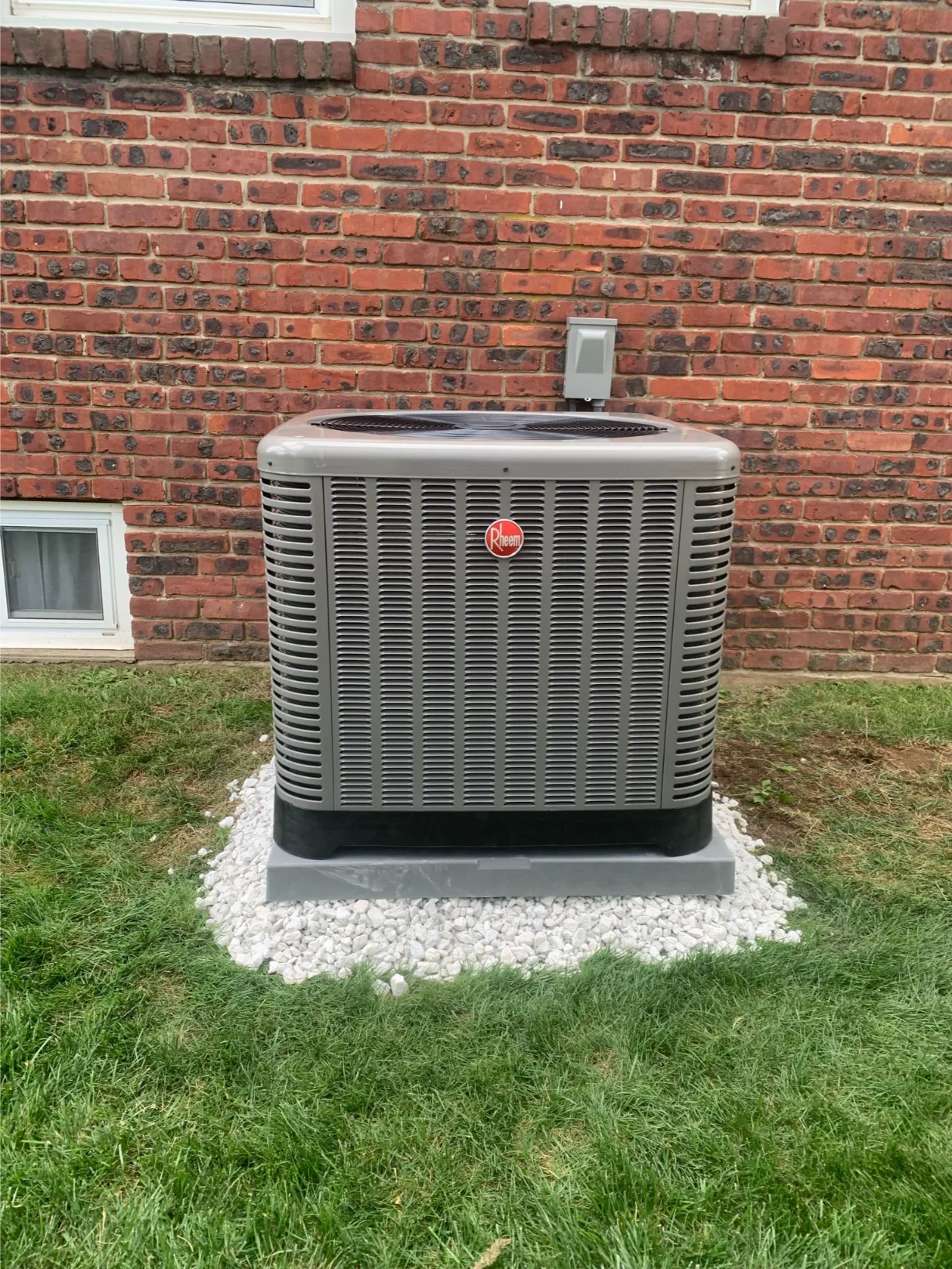 heem outdoor AC unit newly installed against a brick residential wall