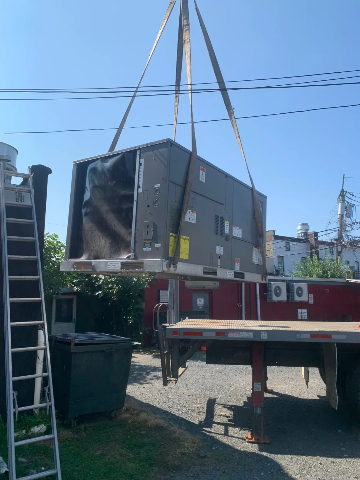 large commercial HVAC unit being lifted by a crane, indicating a heavy-duty installation