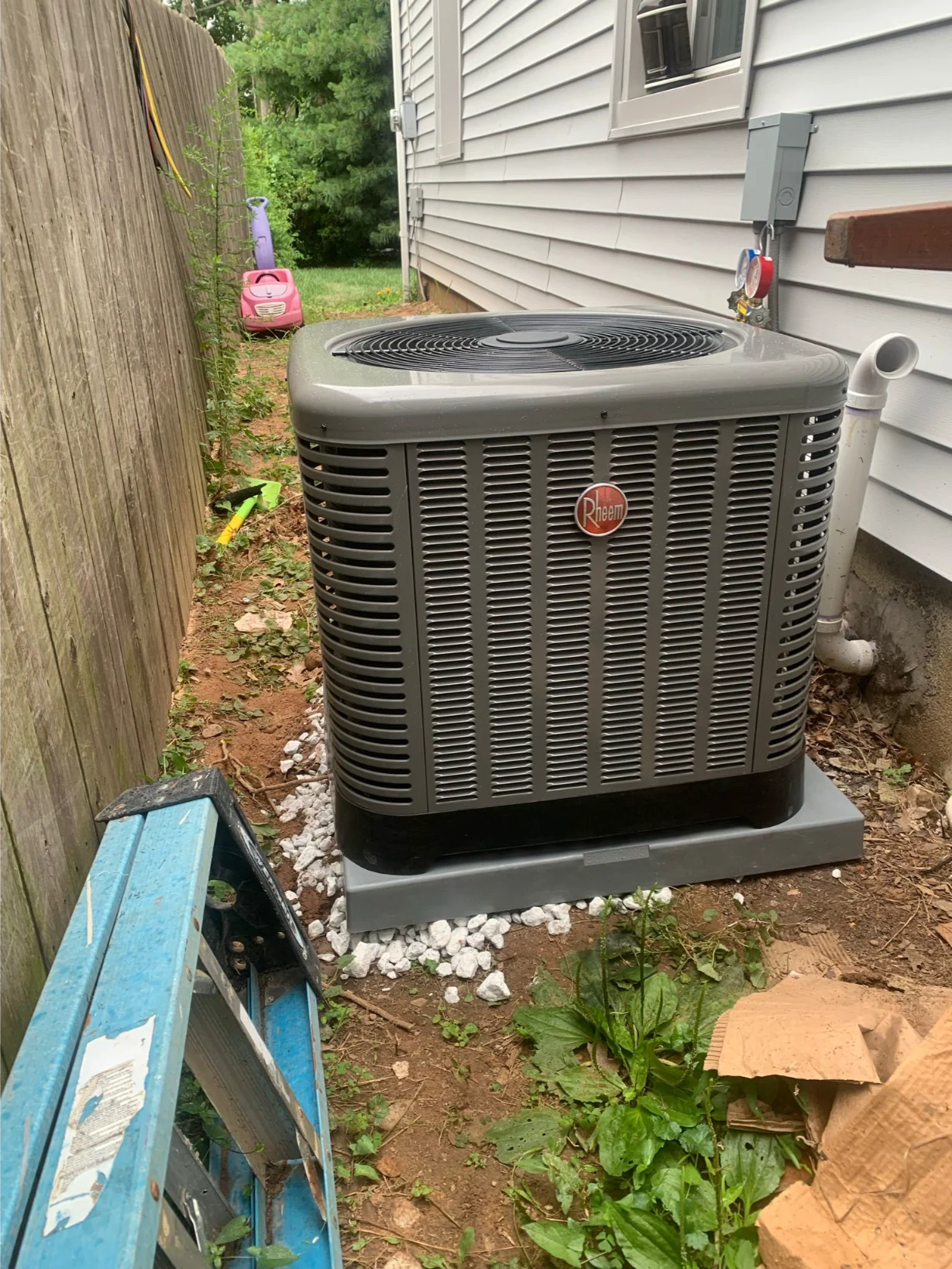 outdoor Rheem AC unit installation in progress or recently completed, with a ladder nearby